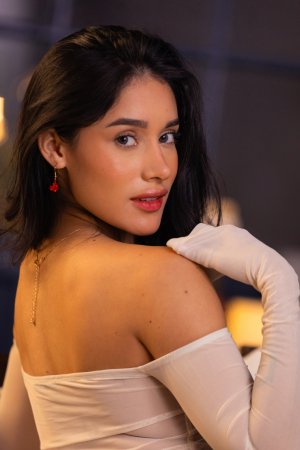 Carolina Guerrero teases in denim shorts and white off shoulder top, legs spread on bed, red earrings gleaming — Carolina Guerrero #4