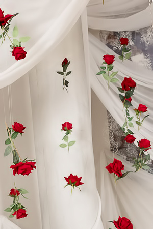 Lesly Clap teases in white lace and blue heels amid red roses, posing nude under a chandelier