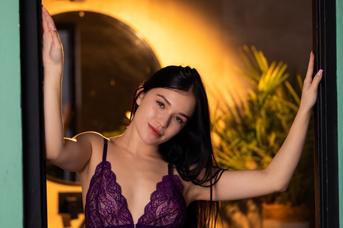 Wikki K strips to nude in warm bedroom light, purple lace sliding down her curves as she poses — Wikki K #5