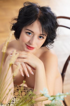 Sugar Ann bares her big tits in black lingerie, sitting on a chair, inviting you closer on the wooden floor — Sugar Ann #16