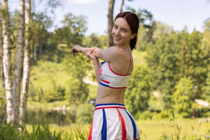 Emma A teases in cheerleader outfit outdoors, topless on white blanket, smiling and posing — Emma A #1