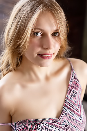 Soft skin yields as Sonya Elf poses nude on chair, skirt slipping to reveal bare curves in bedroom