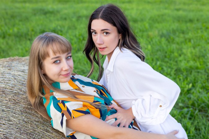 Arete and Yeva, sun-warmed skin pressed close, fingers tracing wet heat on hay bales in the field — Arete & Yeva #2