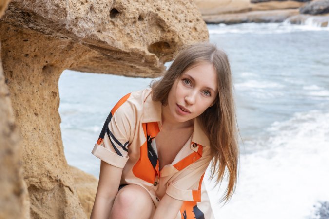 Naomi A sits nude on beach rocks spreading her legs open for the ocean breeze in Tempting Cave — Naomi A #1