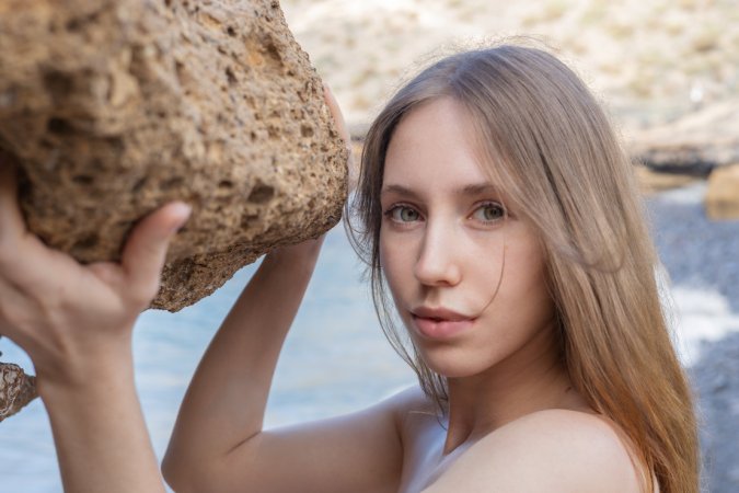 Naomi A sits nude on beach rocks spreading her legs open for the ocean breeze in Tempting Cave — Naomi A #12