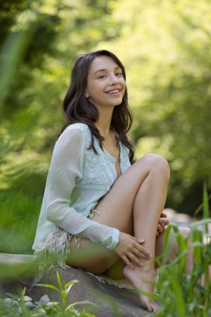 Olivia Linz stands barefoot in the forest, nude and posing under natural light, her curves glowing green — Olivia Linz #2