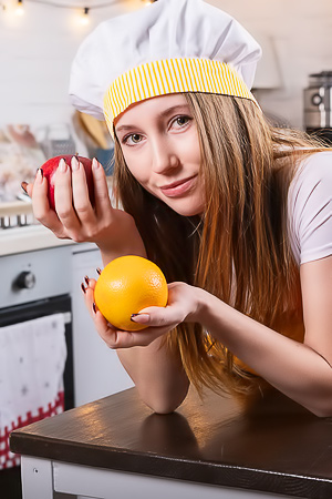 Naomi A poses solo in a festive kitchen, blonde and bare in white lingerie, teasing with fruits by the window
