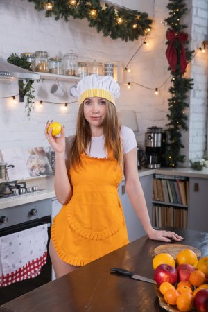 Naomi A poses solo in a festive kitchen, blonde and bare in white lingerie, teasing with fruits by the window — Naomi A #1