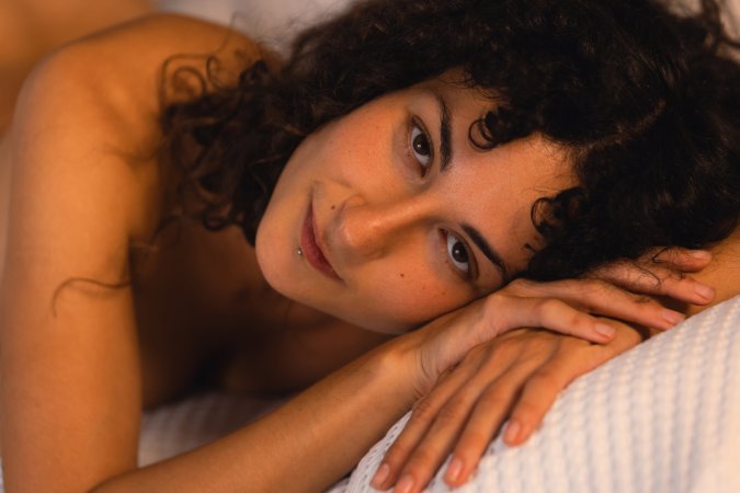 Ajsha teases in red lingerie on a bed with bookshelves behind her curly hair and nude poses — Ajsha #24
