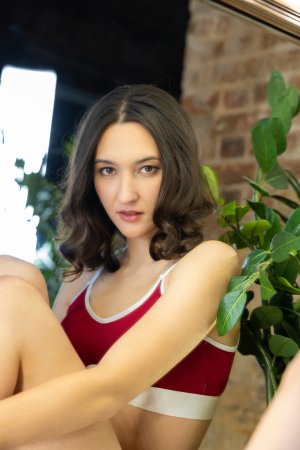 Colette Kai kneels and poses topless in red lingerie before a mirror, her gaze holding you captive in slow, silent desire — Colette Kai #2