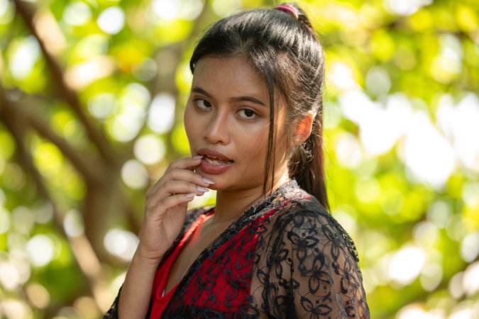 Bua stripping in red lingerie outdoors, topless posing with black lace against green foliage — Bua #2