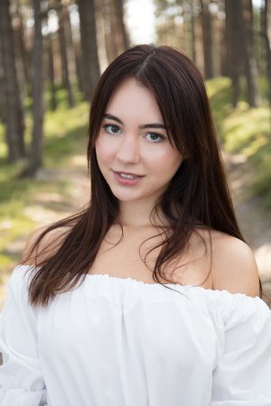 Dellia barefoot in the forest, smiling as she drops her dress and holds wildflowers, natural light teasing every curve — Dellia #2