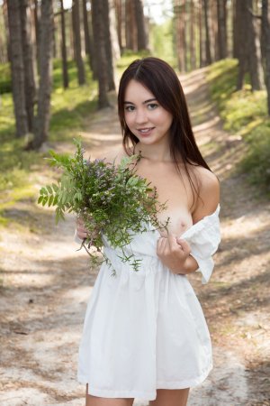 Dellia barefoot in the forest, smiling as she drops her dress and holds wildflowers, natural light teasing every curve — Dellia #4